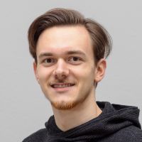 Luis Wolf - Developer: Smiling man with straight, dark brown hair, black corduroy hoodie and brown eyes.