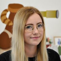 Julia Sukop - Designer: Slightly smiling woman with long blonde hair and thin, golden glasses.